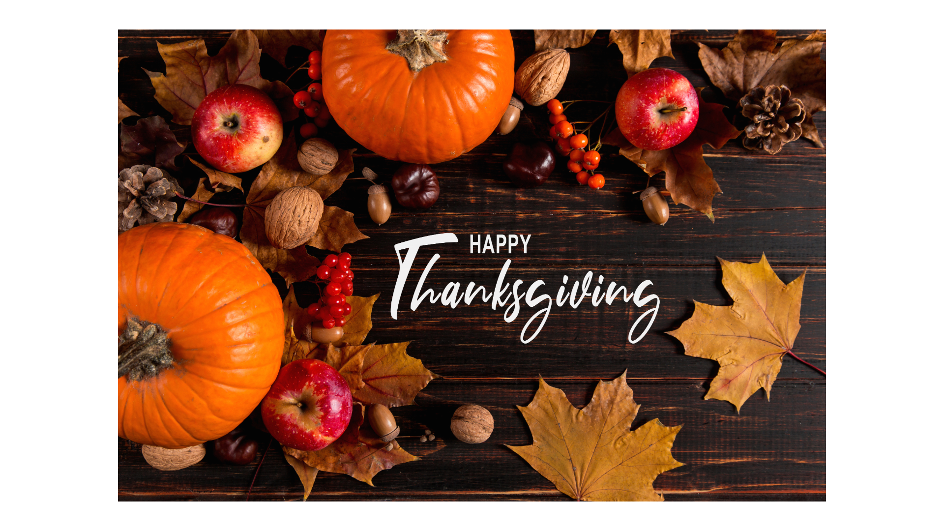 Pumpkins and leaves on a table with Happy Thanksgiving written in middle