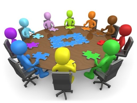 Group of individuals sitting around a circle table with a puzzle piece in front of them 