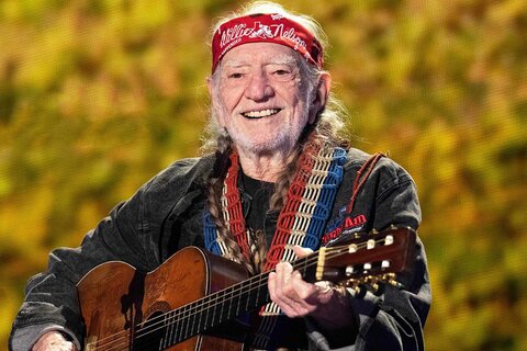 a portrait of Willie Nelson holding his guitar